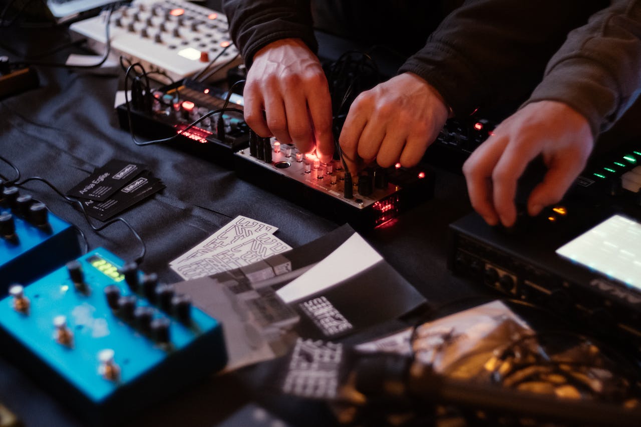 Close-up of hands adjusting knobs on audio equipment in a music studio.